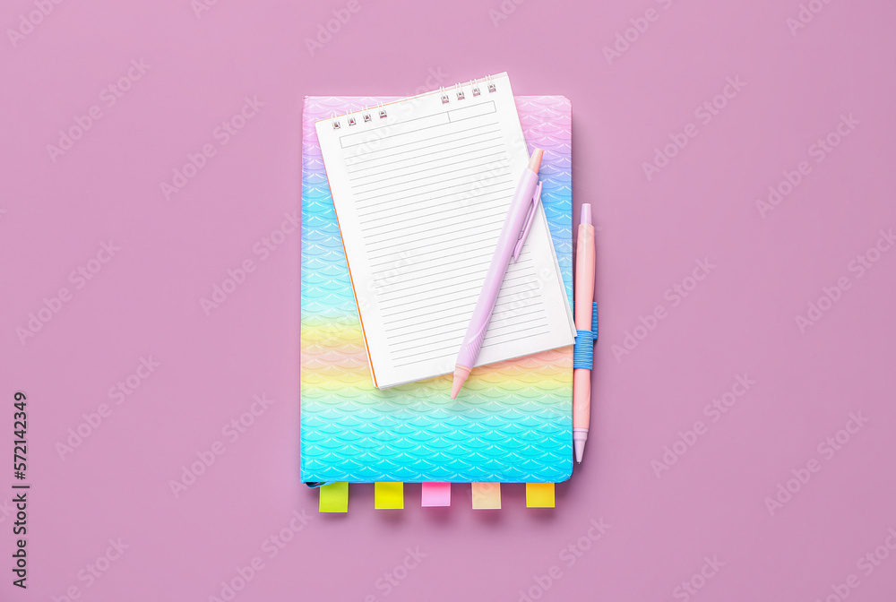 Notebooks and pens on lilac background