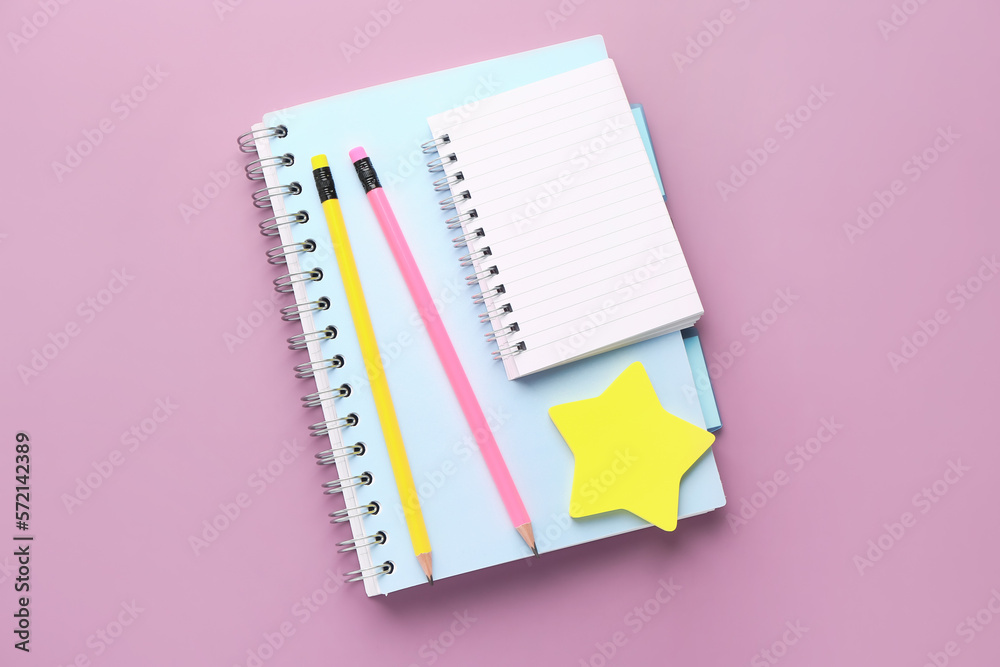 Notebooks, pencils and sticky notes on lilac background