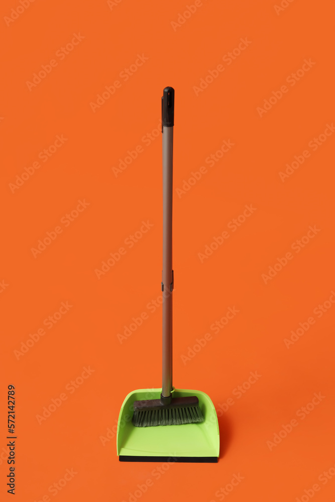 Plastic dustpan with cleaning broom on color background