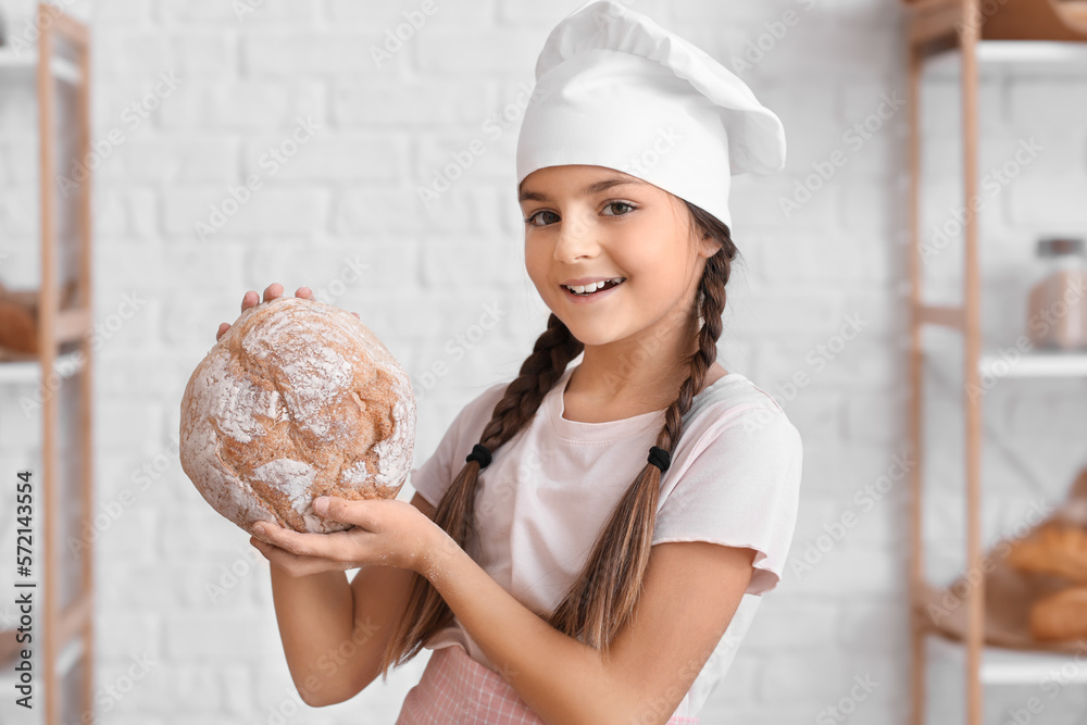 Little baker with fresh bread in kitchen