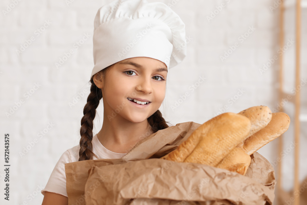 Little baker with fresh baguettes in kitchen, closeup