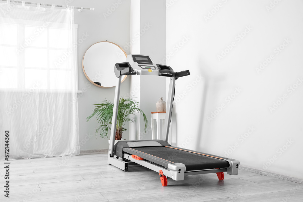 Modern treadmill in interior of light room