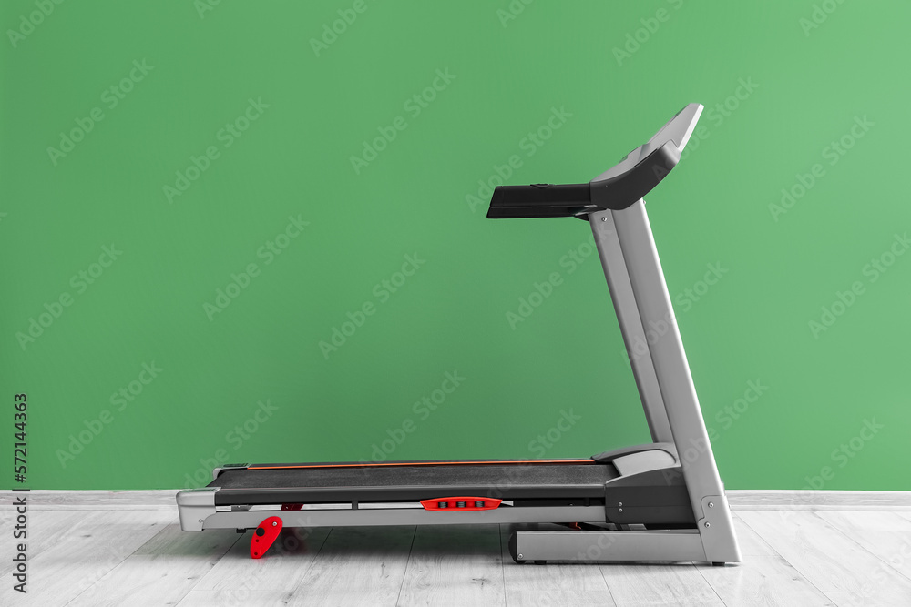 Modern treadmill near green wall