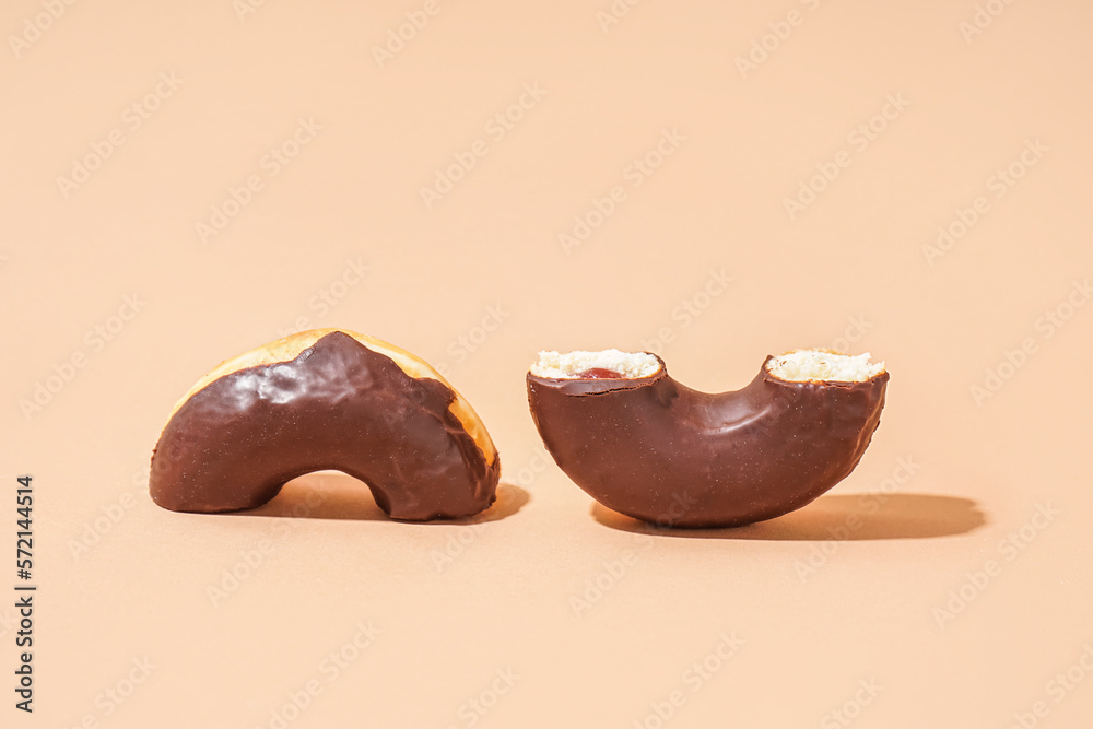 Halves of delicious chocolate donut on beige background