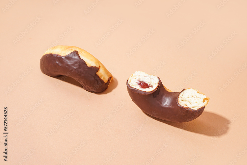 Halves of delicious chocolate donut on beige background