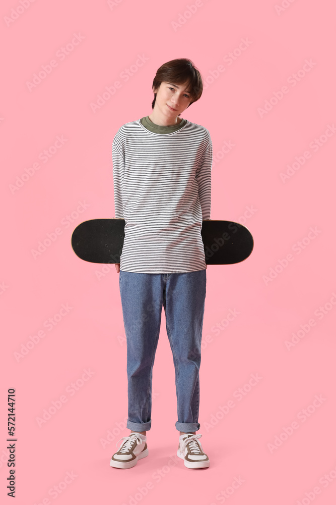 Teenage boy with skateboard on pink background