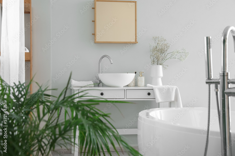 Table with sink and flowers in interior of light bathroom