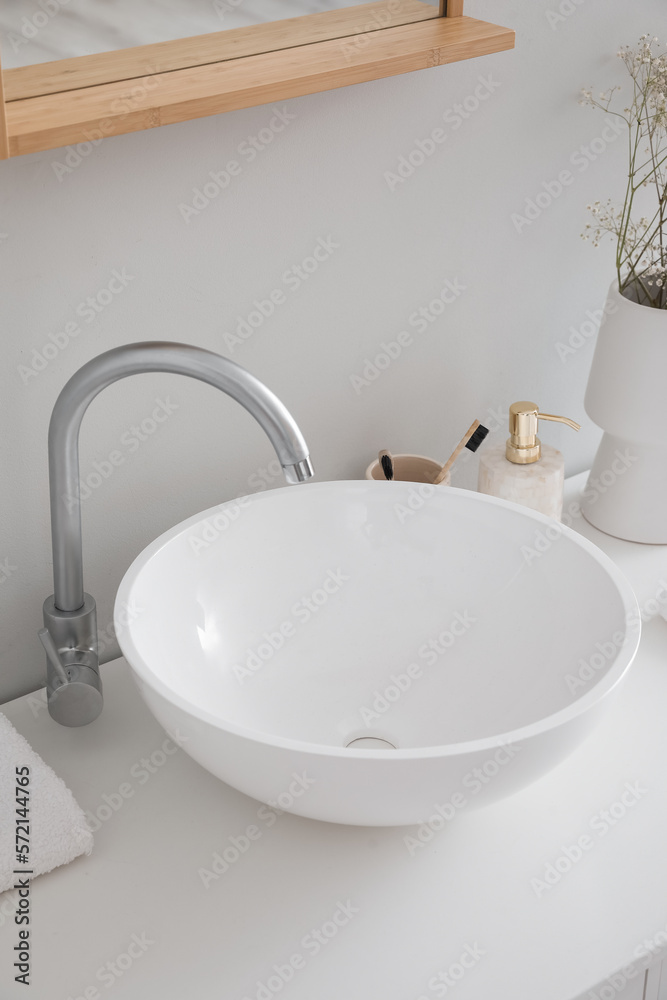 White sink and bath accessories on table in room, closeup