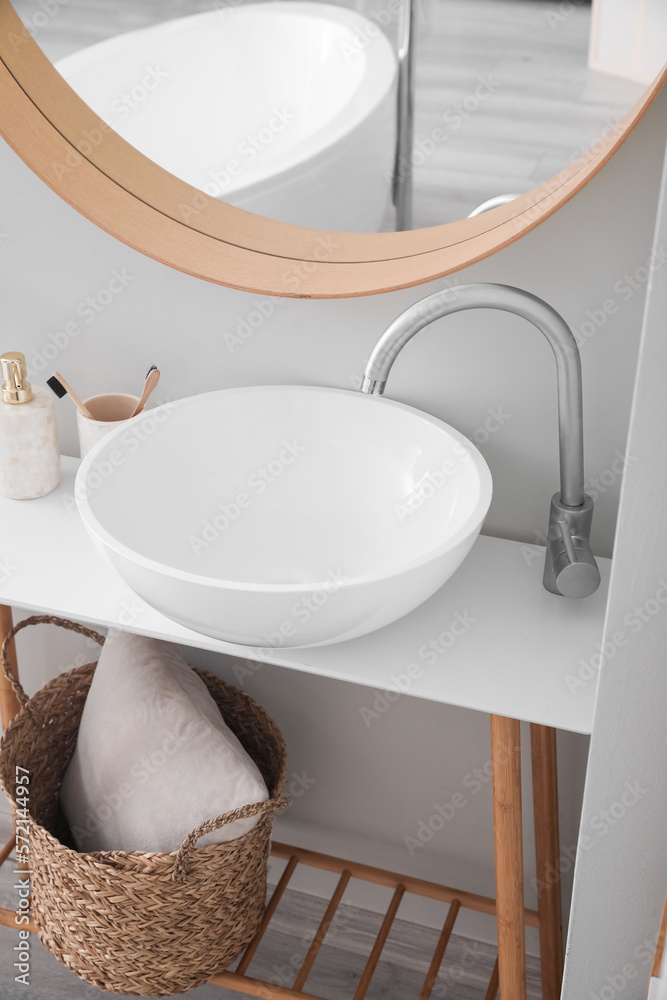 Table with modern sink, mirror and accessories in bathroom