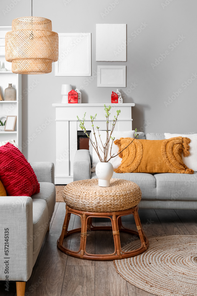 Interior of living room with sofas, houseplant and house candle holders on fireplace