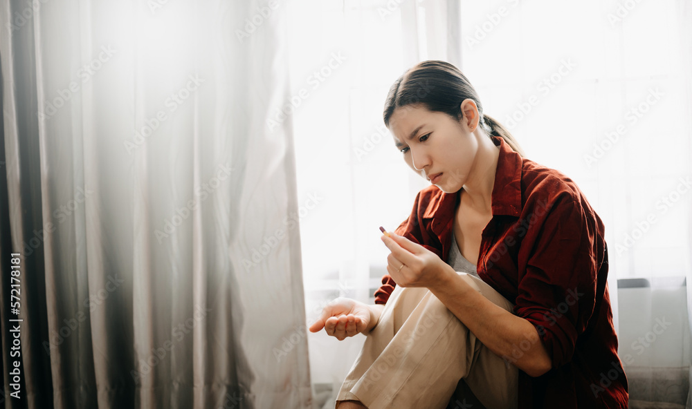  woman sit Depression Dark haired  pensive glance Standing with glass of water and pills by window a