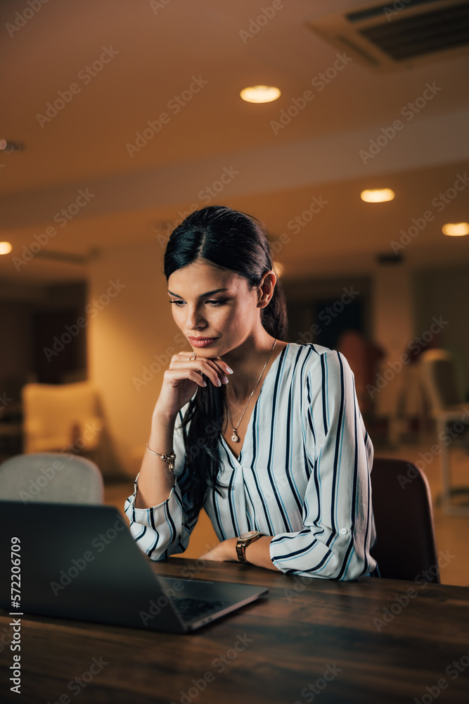 Serious female boss checking the list of job applicants, looking at the laptop.