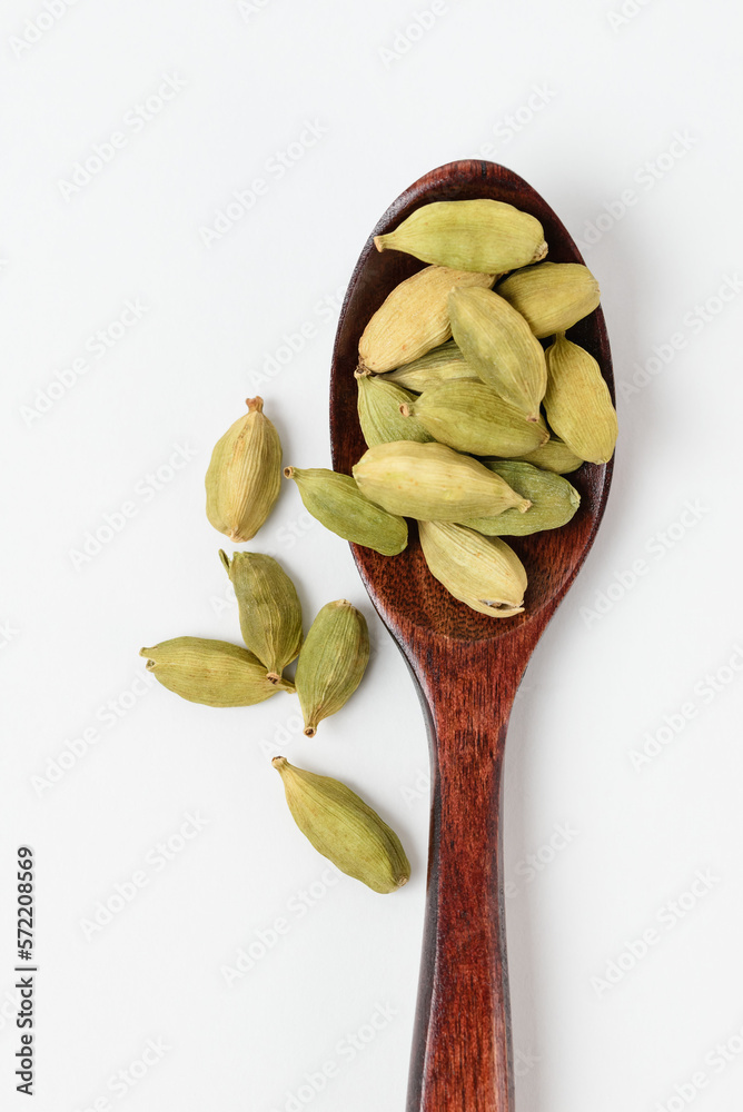 Top view of fragrant oriental spices cardamom pods in brown wooden spoon