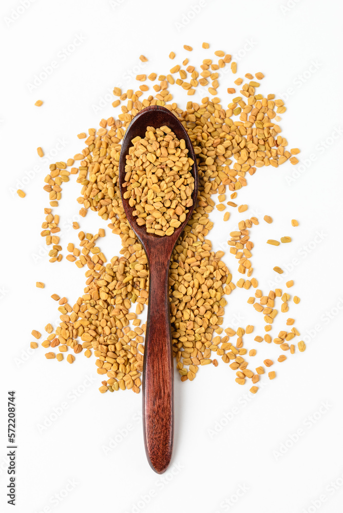 Brown wooden spoon whole of dry yellow fenugreek seeds or shambhala, helba seeds isolated top view