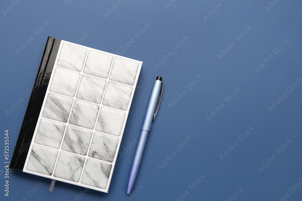 Stylish notebook and pen on blue background