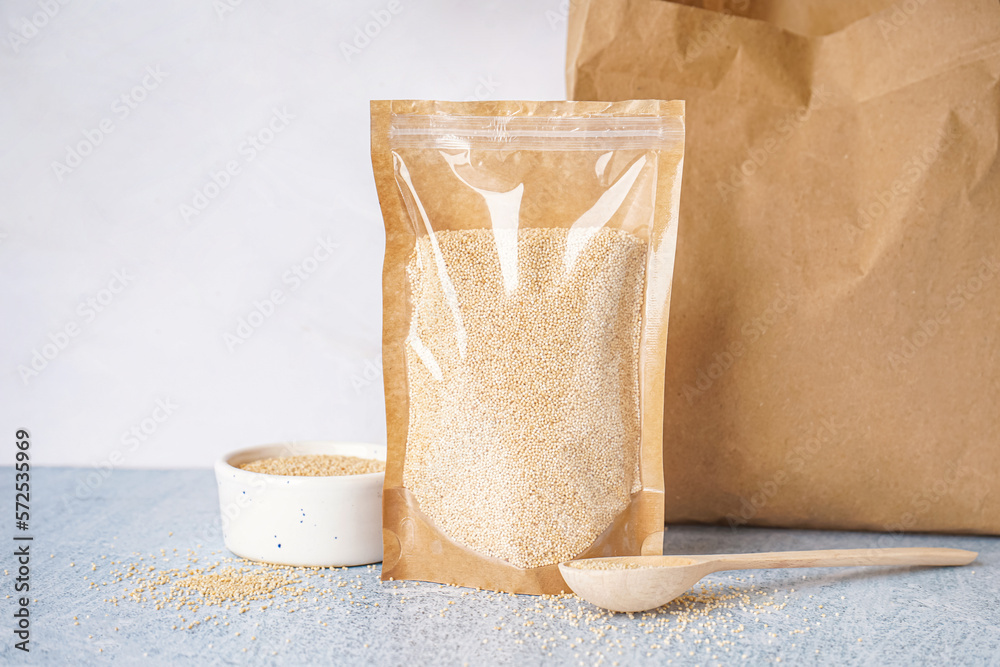 Paper bag, bowl and spoon of amaranth seeds on table