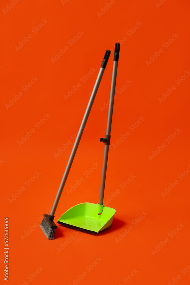 Plastic dustpan with cleaning broom on color background