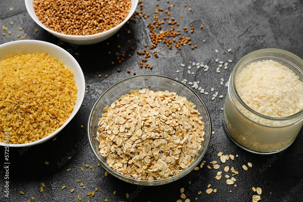 Bowls of different cereals on dark background