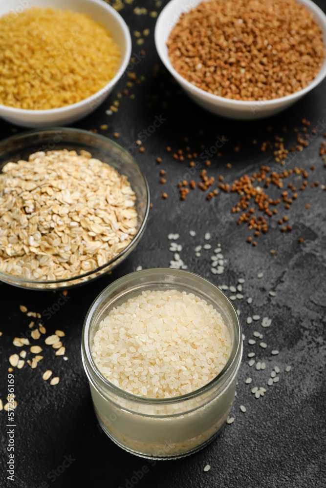 Bowls of different cereals on dark background