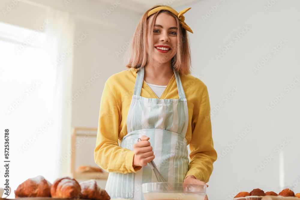 Female baker making dough at table in kitchen