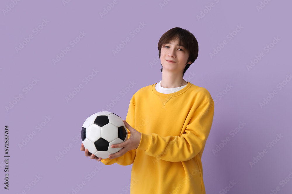 Teenage boy with soccer ball on lilac background