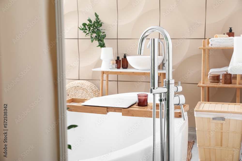 Interior of bathroom with modern bathtub and laptop on board