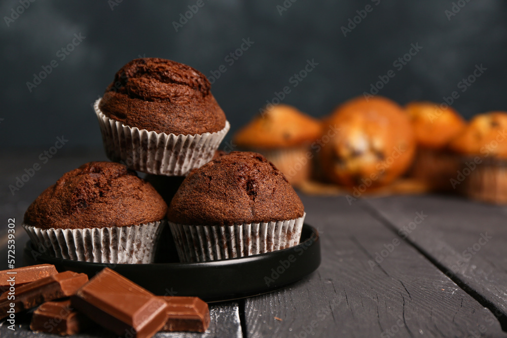 Plate of tasty chocolate muffins on dark wooden background