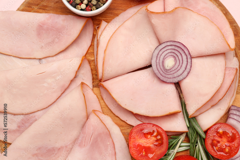 Board with tasty slices of ham, onion, tomatoes and rosemary on pink background