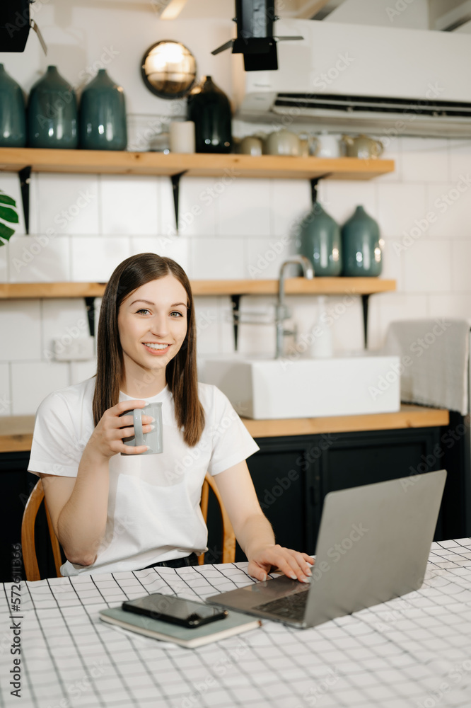 Confident beautiful Asian businesswoman typing laptop computer and digital tablet while holding coff