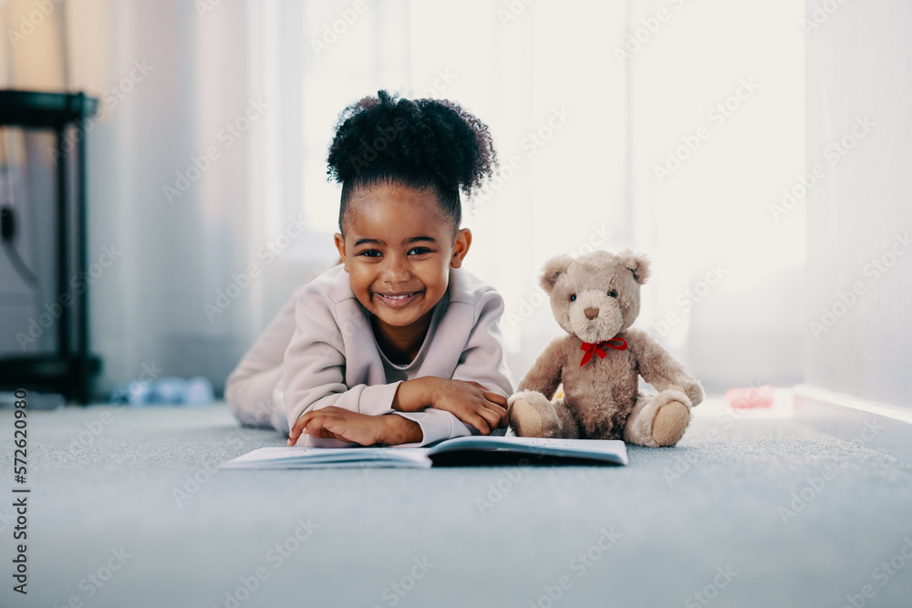 Happy toddler girl reading a book at home