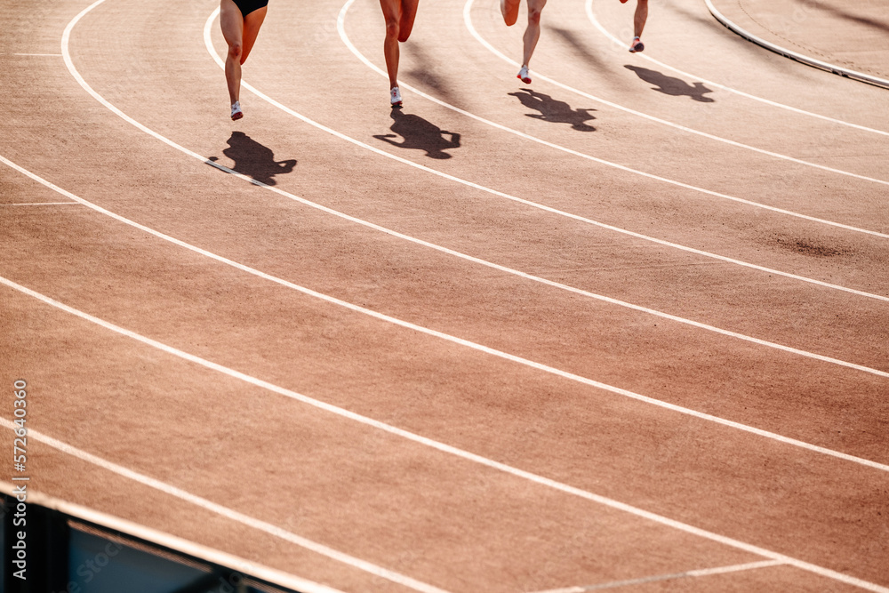 group female athletes running track of stadium