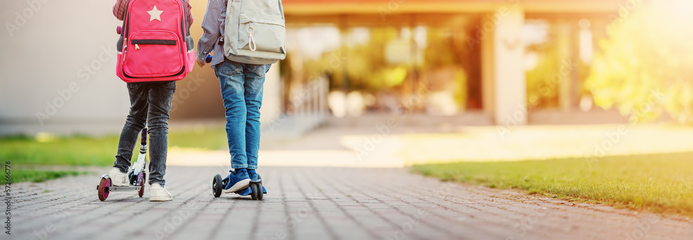 Girl and boy riding scooters in school to study at it.