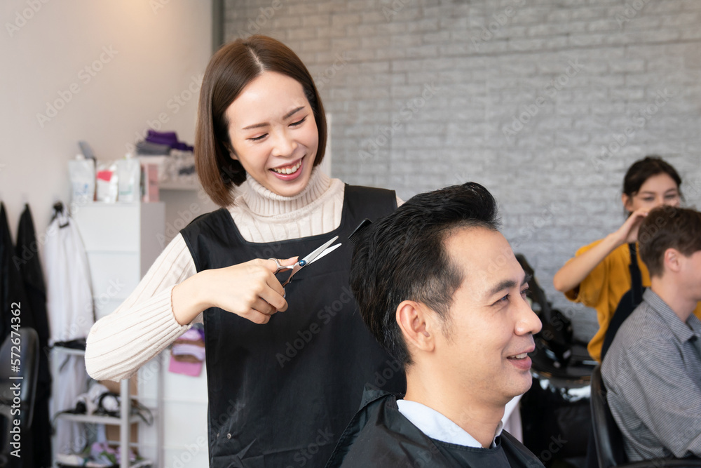 Asian female hairdresser making haircut for two male customer with male hairstyle in qualified barbe