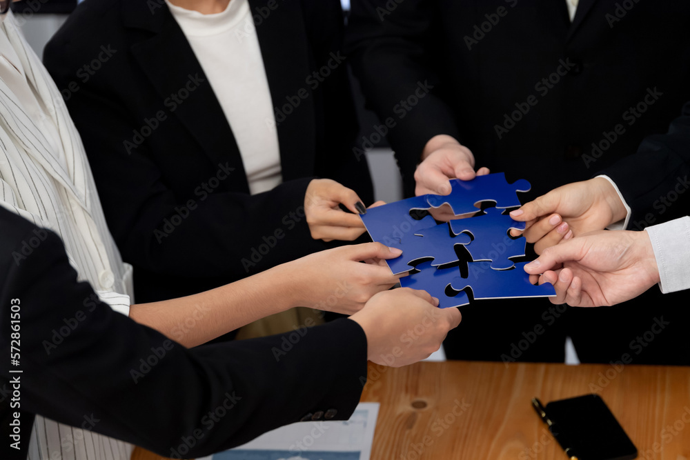 Closeup top view business team of office worker putting jigsaw puzzle together over table filled wit