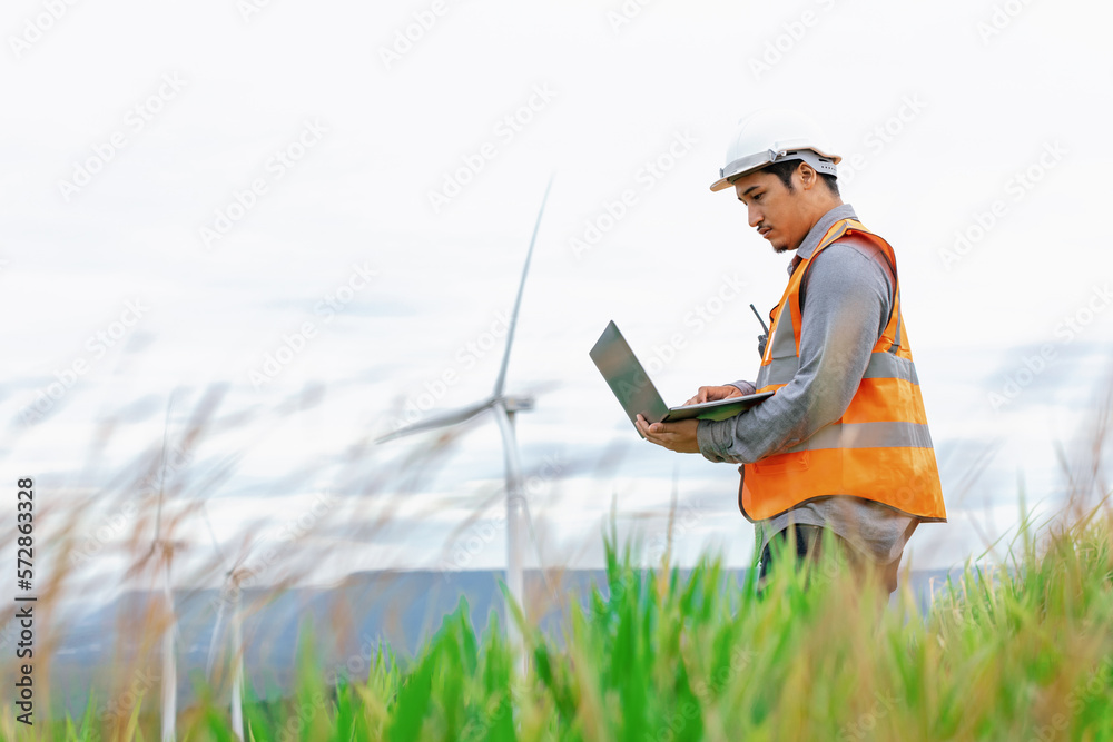 Engineer working on a wind farm atop a hill or mountain in the rural. Progressive ideal for the futu