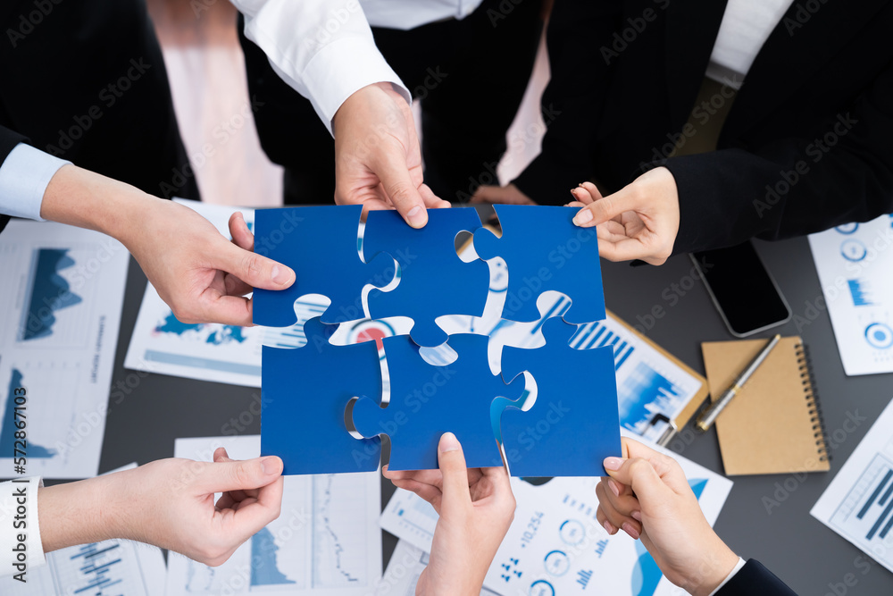 Closeup top view business team of office worker putting jigsaw puzzle together over table filled wit