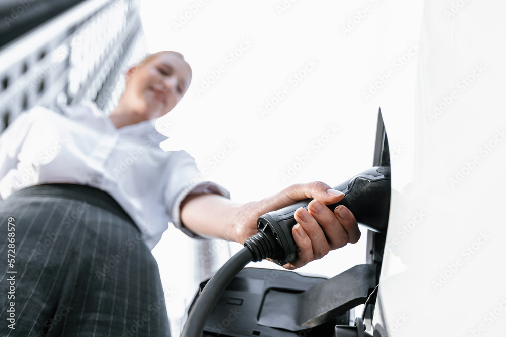 Fisheye view focus hand holding, inserting, plugging ev charger from public charging station for ele