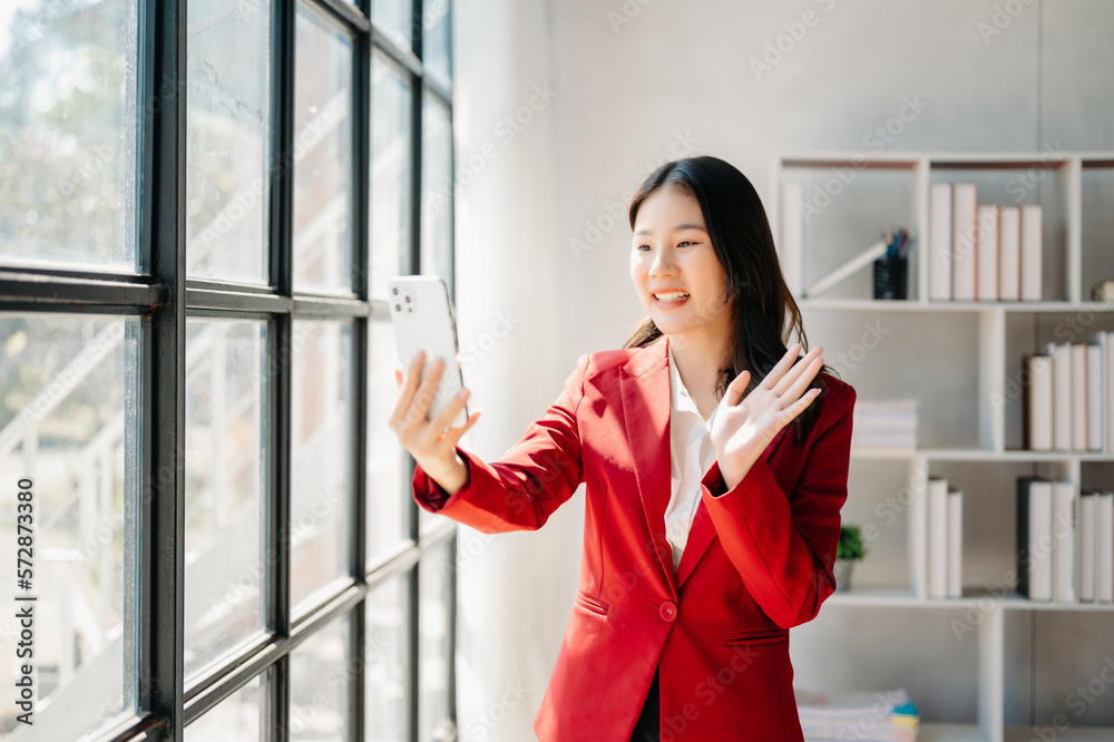 Business asian woman Talking on the phone and using a laptop with a smile while sitting at office