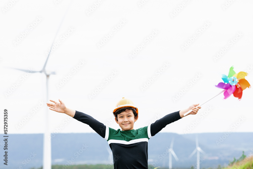 Progressive young asian boy playing with wind pinwheel toy in the wind turbine farm, green field ove