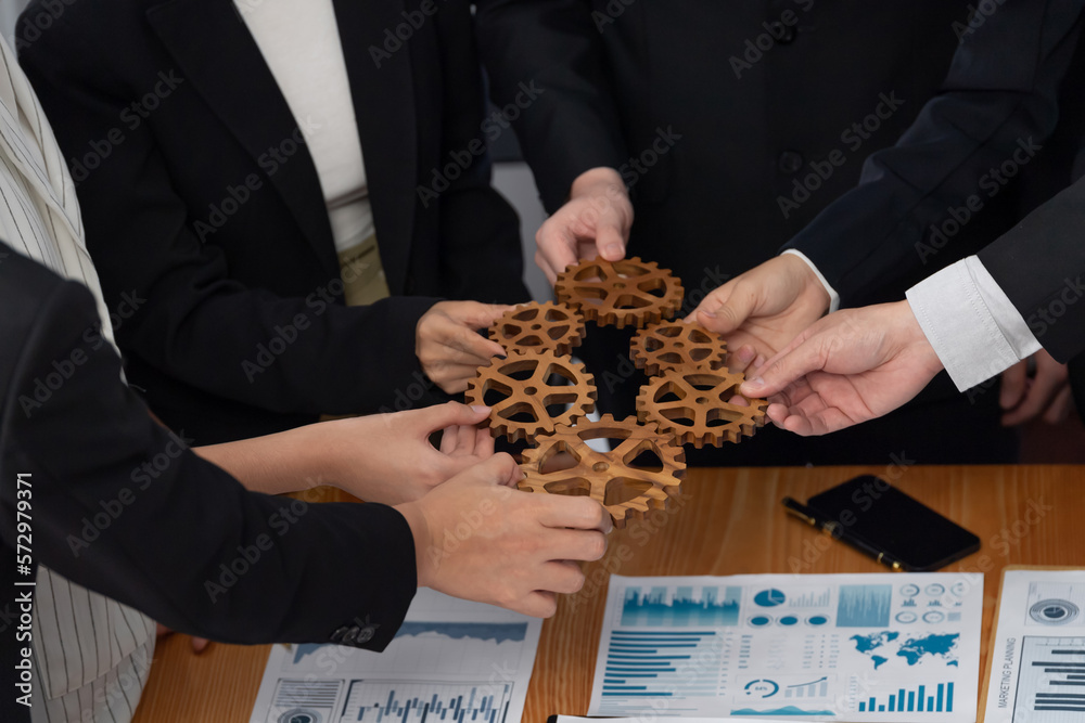 Closeup top view businesspeople hand holding gear and join together over meeting table with financia