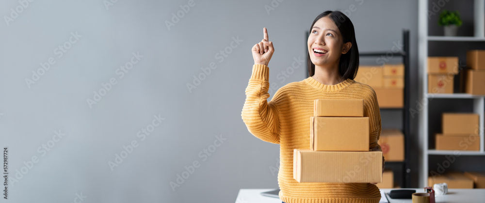 Adorable Asian woman holding the parcel boxes for her customers, online Sme business concept.