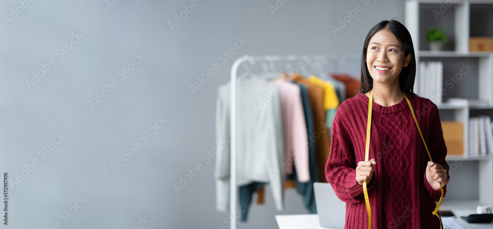 Young confident Asian woman who own cloth shop standing in her studio while measuring the size for h