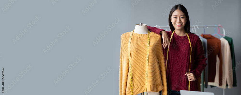 Young confident Asian woman who own cloth shop standing in her studio while measuring the size for h