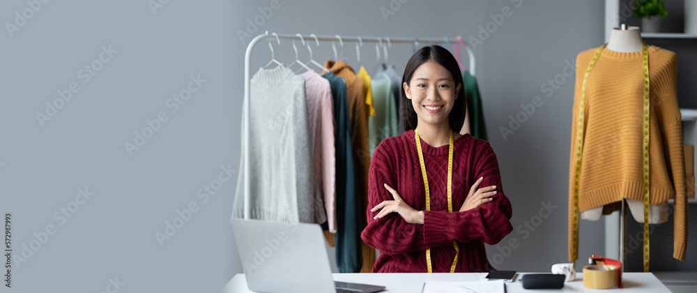 Young confident Asian woman who own cloth shop standing in her studio while measuring the size for h