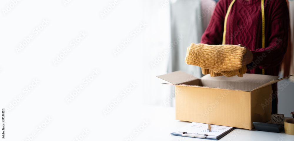 Young Asian shop owner packing her product for customer, putting cloth down in the box, ready to sen