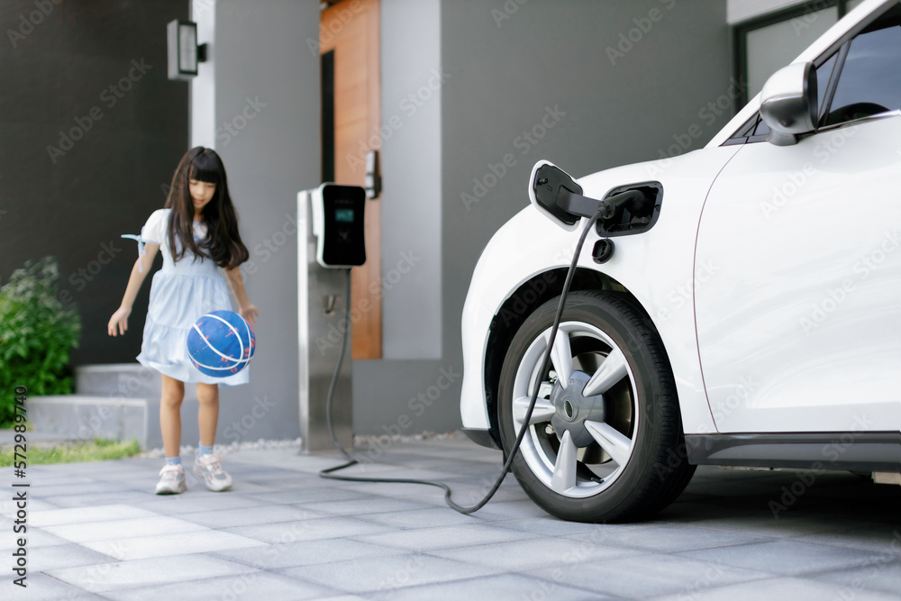 A playful and happy girl playing around at her home charging station providing a sustainable power s