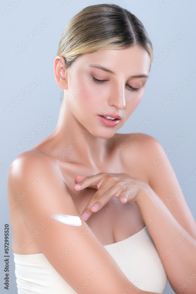 Alluring beautiful woman applying moisturizer cream on her arm for perfect skincare treatment in iso