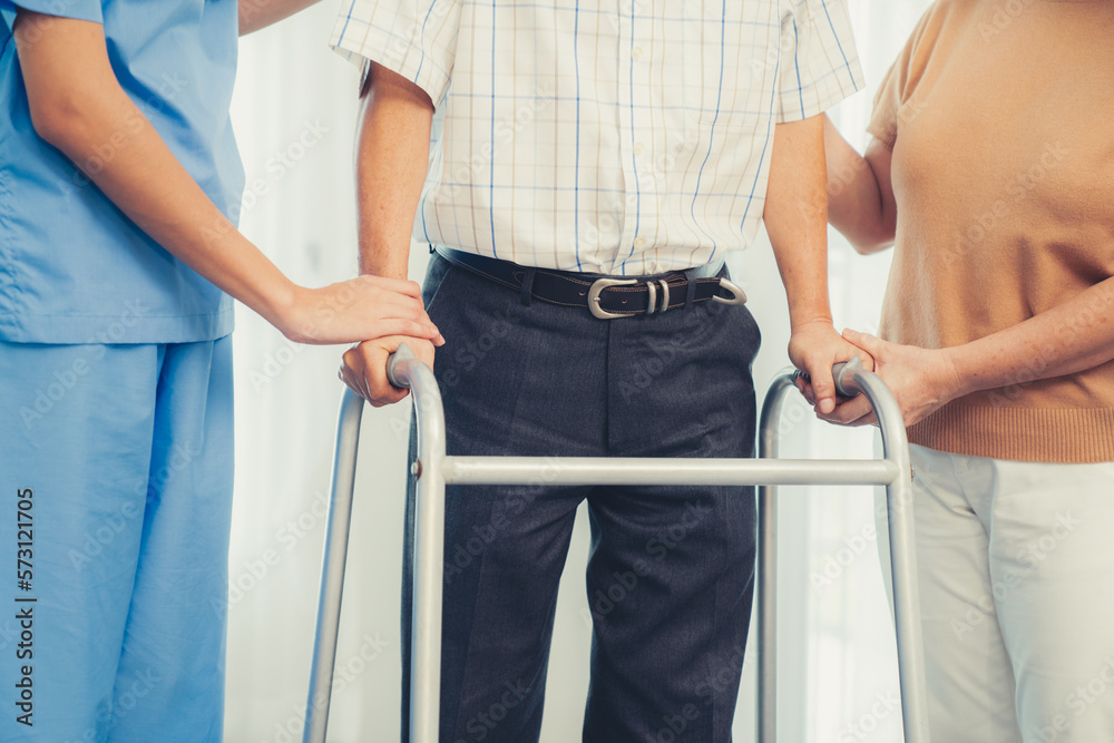 Contented senior man walking as he is helped by his wife and caretaker, walking with the aid of a fo