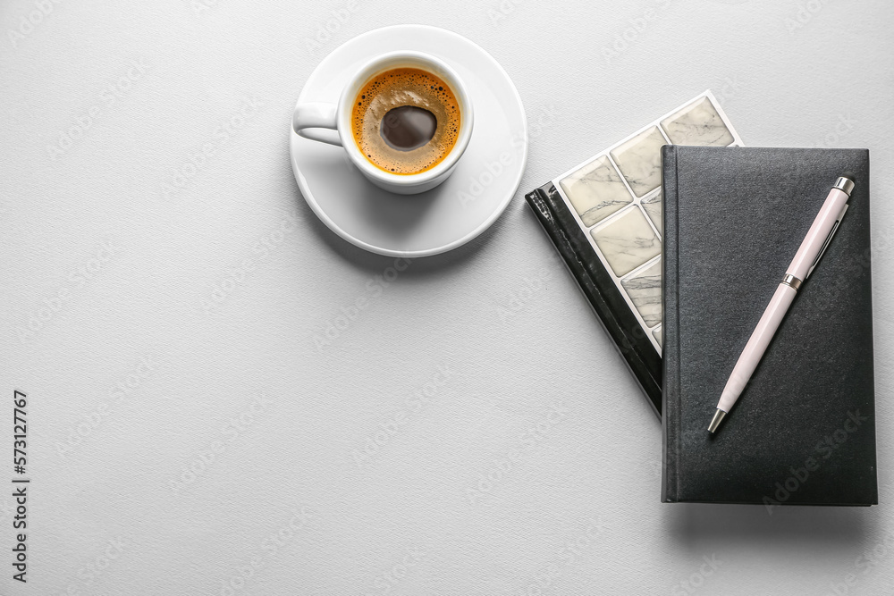 Notebooks, pen and cup of coffee on light background