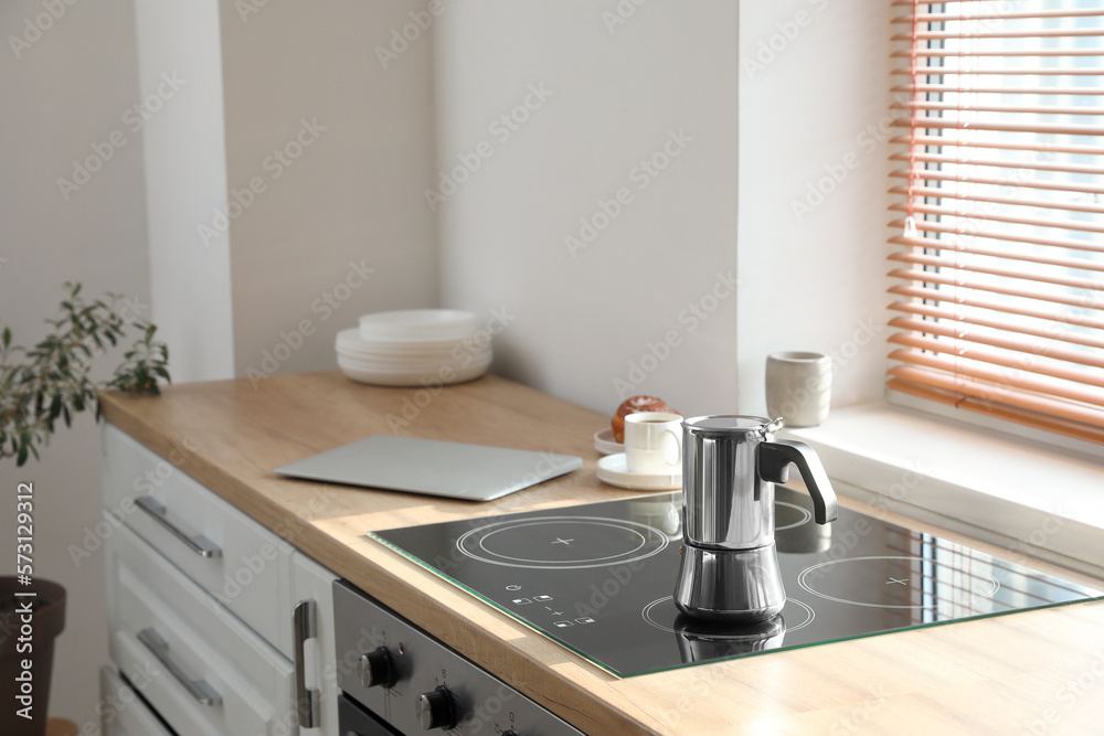 Geyser coffee maker on electric stove in kitchen near window